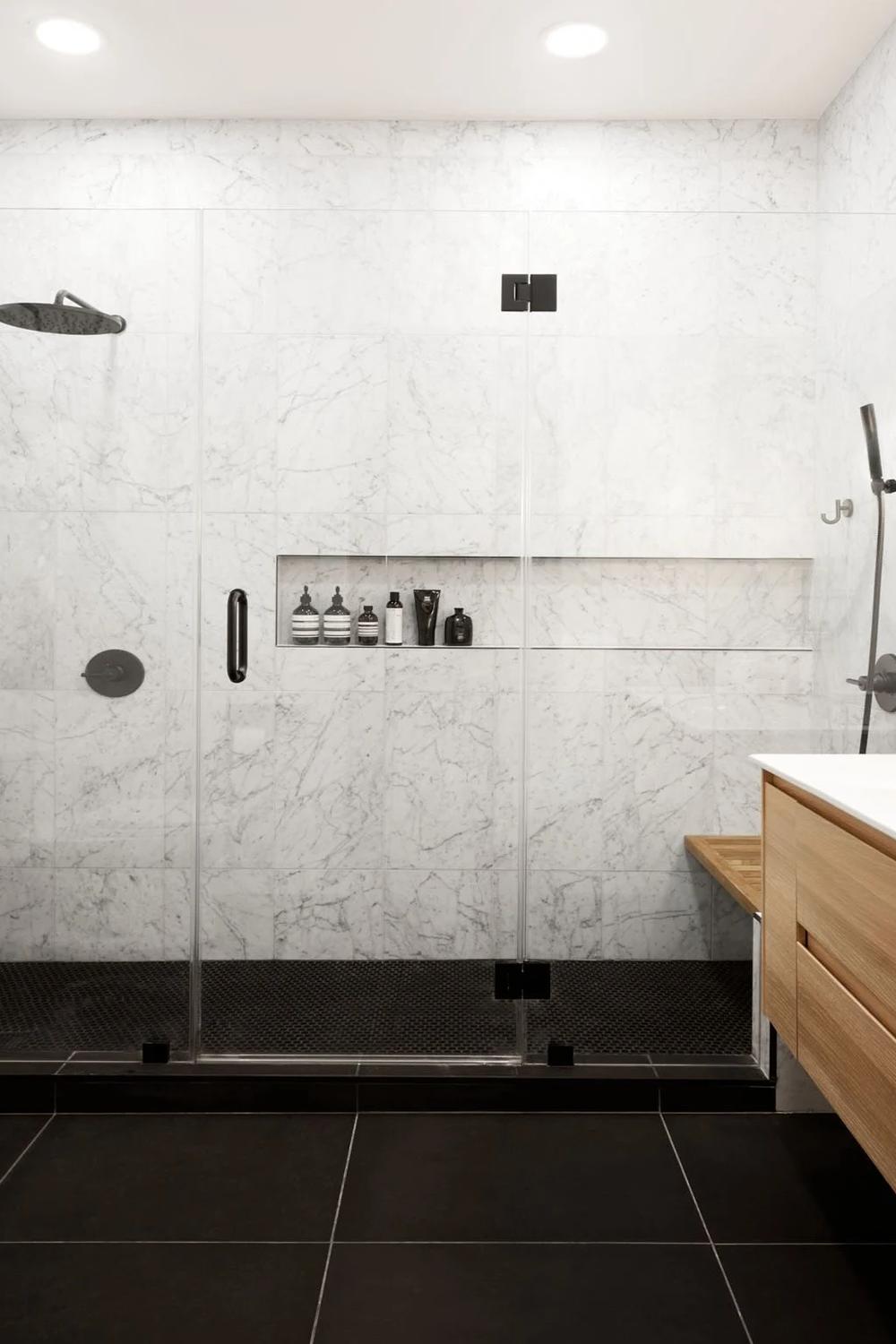 Bathroom with dark shower area and light marble accents