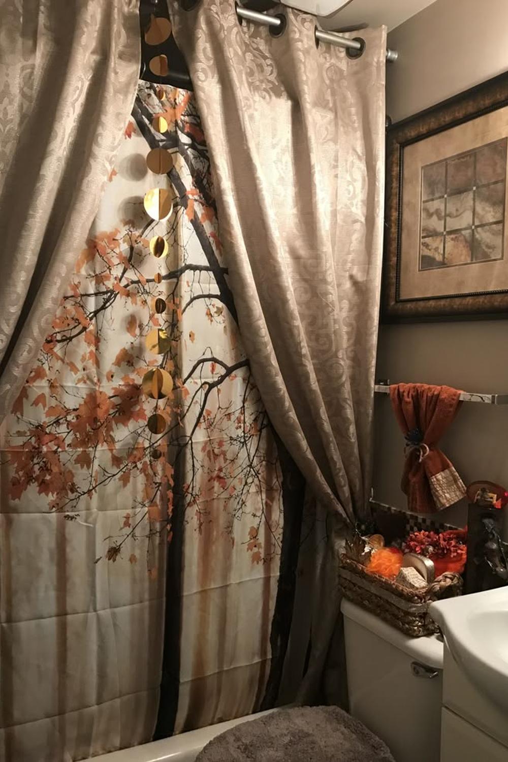 Autumn-themed double shower curtain featuring vibrant trees and a soft beige outer curtain in a warmly decorated bathroom.