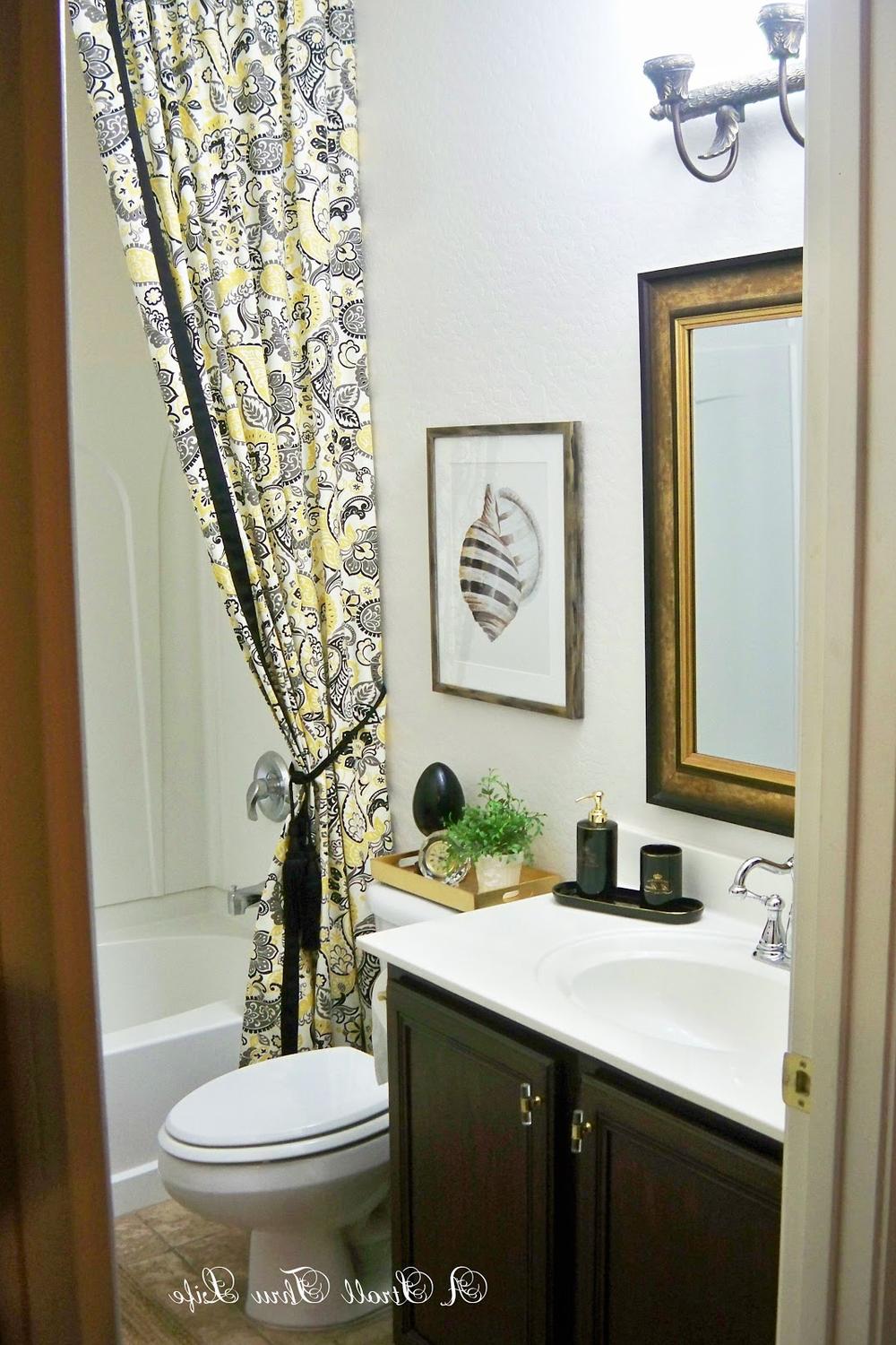 Compact bathroom featuring a vibrant yellow and black paisley double shower curtain, creating a lively atmosphere.