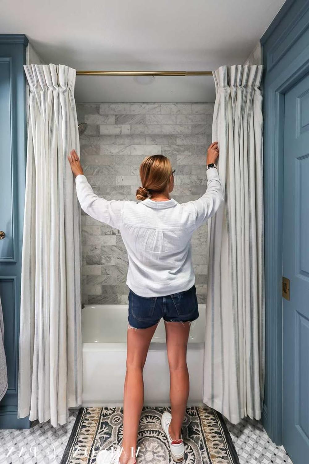 Beautifully arranged bathroom featuring soft blue double shower curtains and an elegant bathtub.