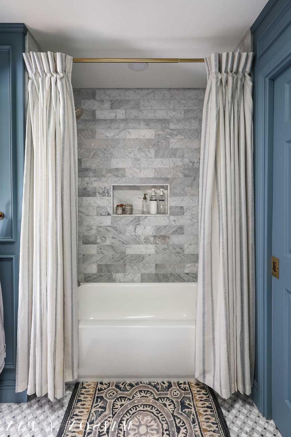 Sophisticated bathroom showcasing beautiful gray marble tiles paired with light double shower curtains.