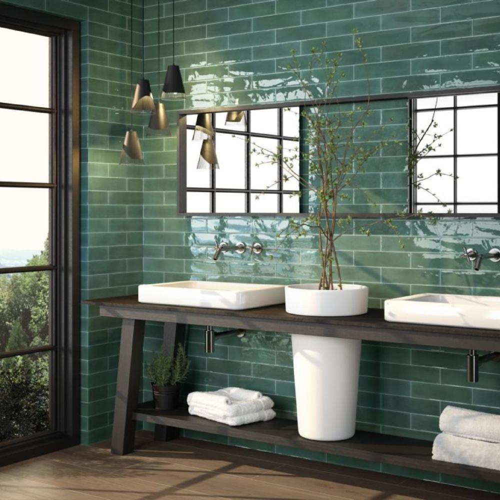 A modern bathroom featuring deep green subway tiles