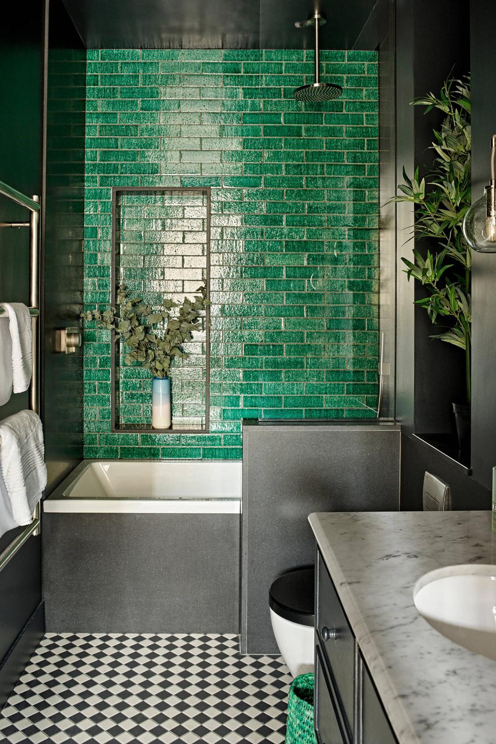 An elegant bathroom featuring an emerald green vanity with modern lighting