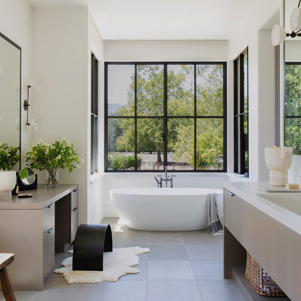 Modern ensuite bathroom featuring a freestanding oval bathtub near a large window.
