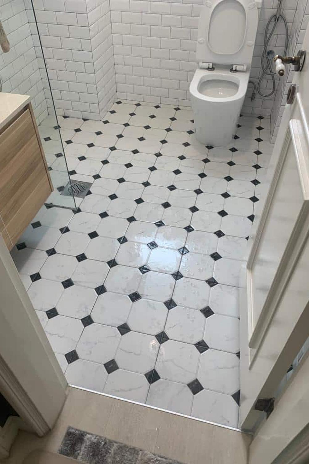Contemporary bathroom with octagonal white tiles and black diamond accents on an epoxy floor.