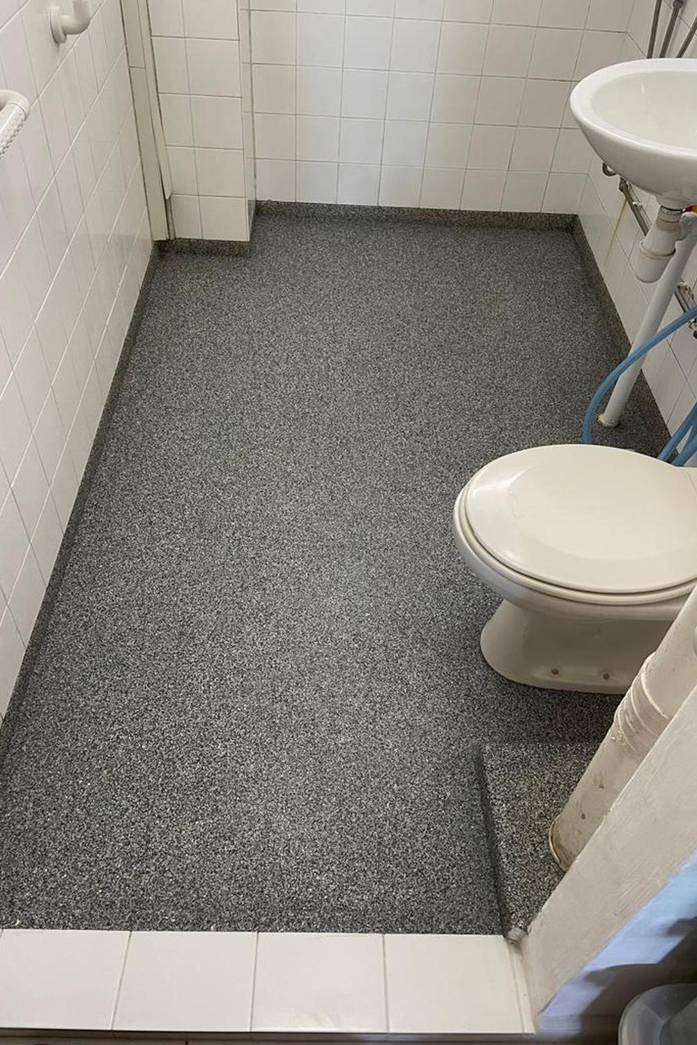 Compact bathroom featuring grey epoxy flooring with speckles, ideal for small spaces.