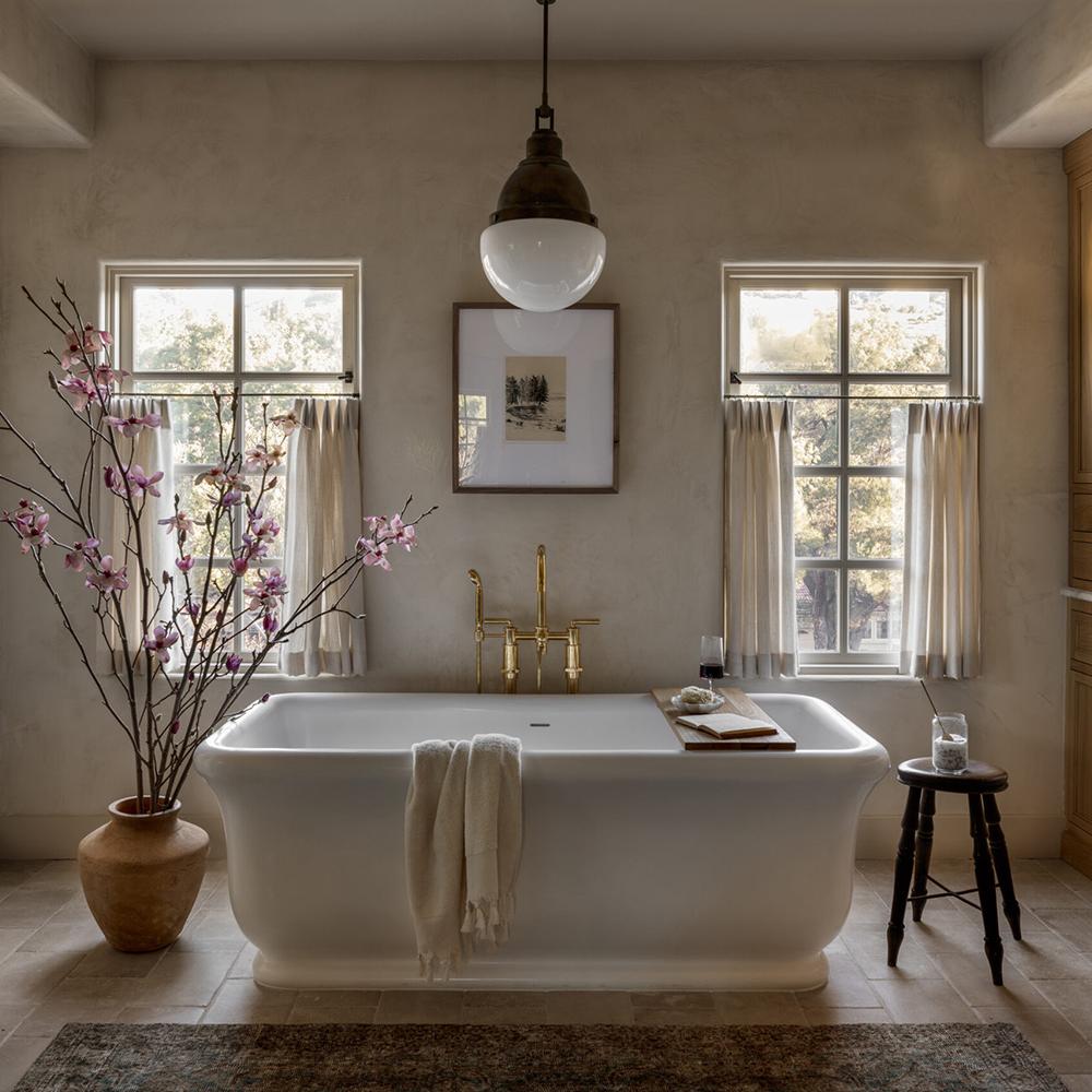 Luxurious farmhouse bathroom featuring a freestanding bathtub and warm lighting.