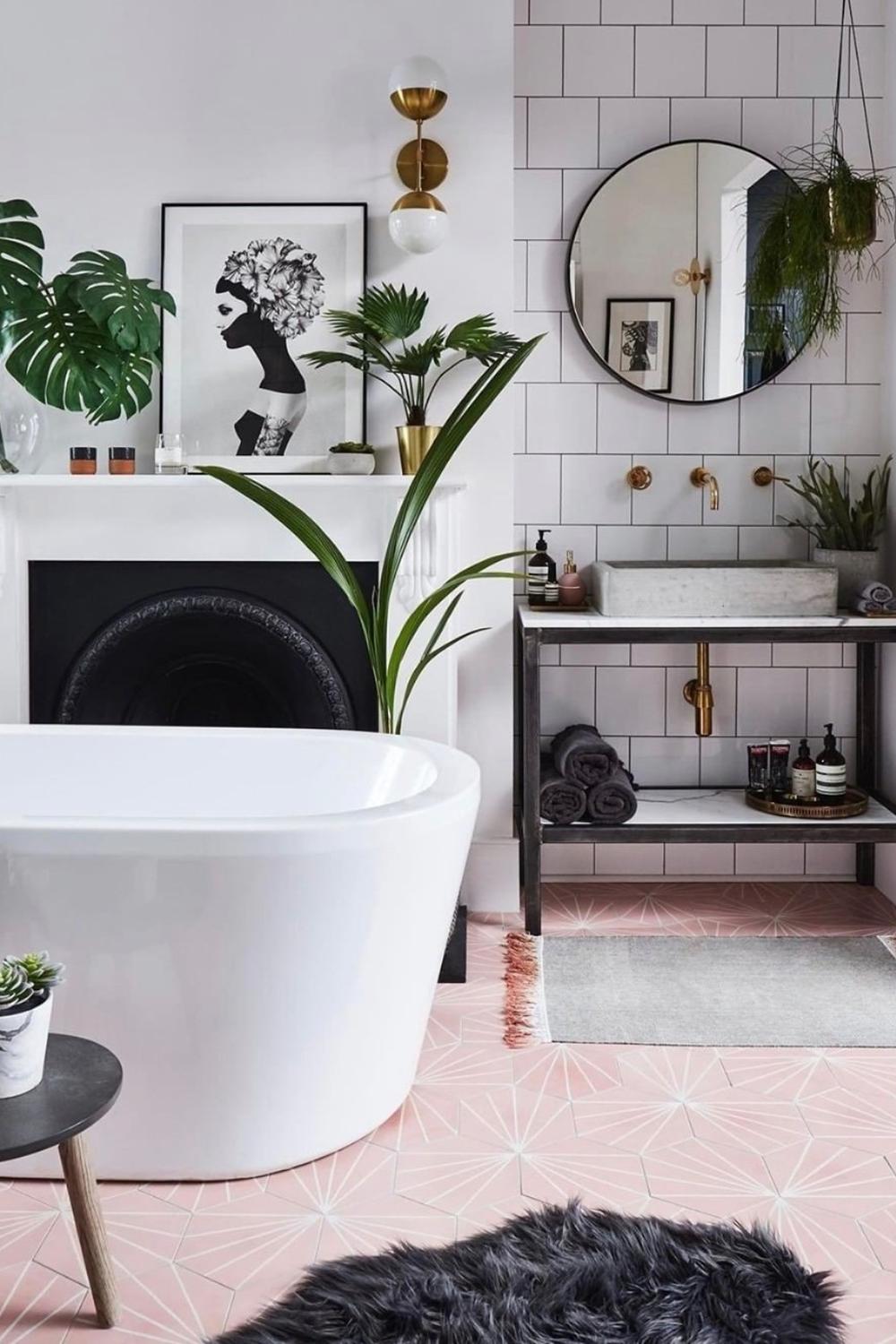 A stylish feminine bathroom featuring a large freestanding bathtub, wall art, and indoor plants adding vibrancy to the space.