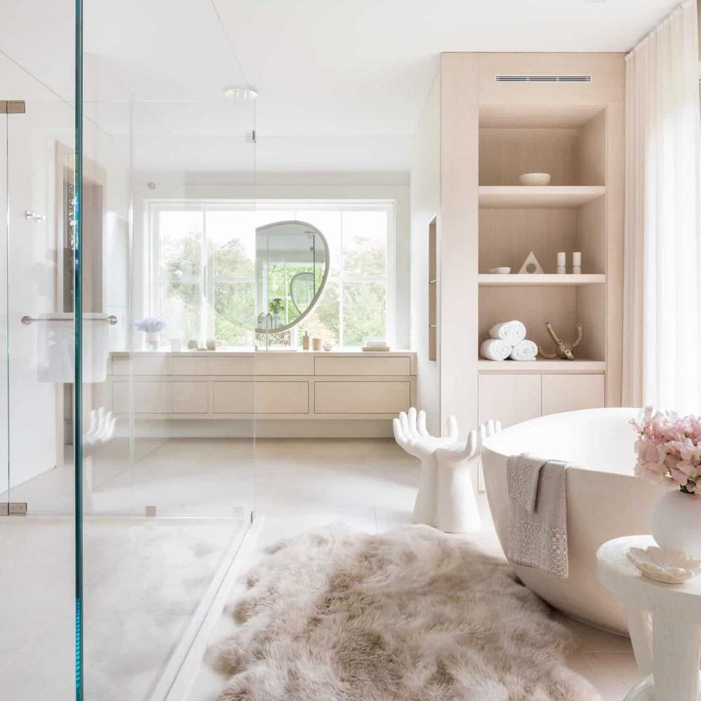 A serene bathroom design with a round freestanding bathtub, an oversized mirror, and soft lighting creating a cozy ambiance.