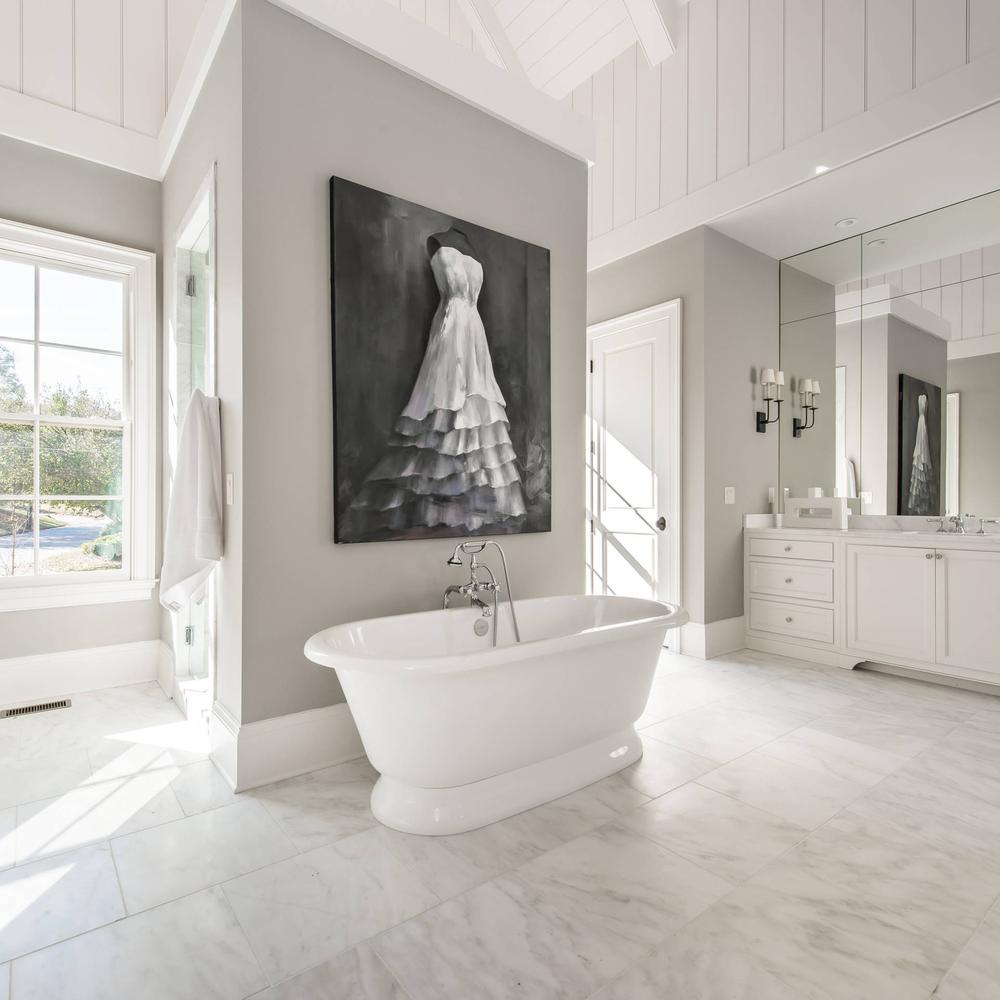 A sophisticated feminine bathroom characterized by a soft color palette, artistic decorations, and luxurious finishes.
