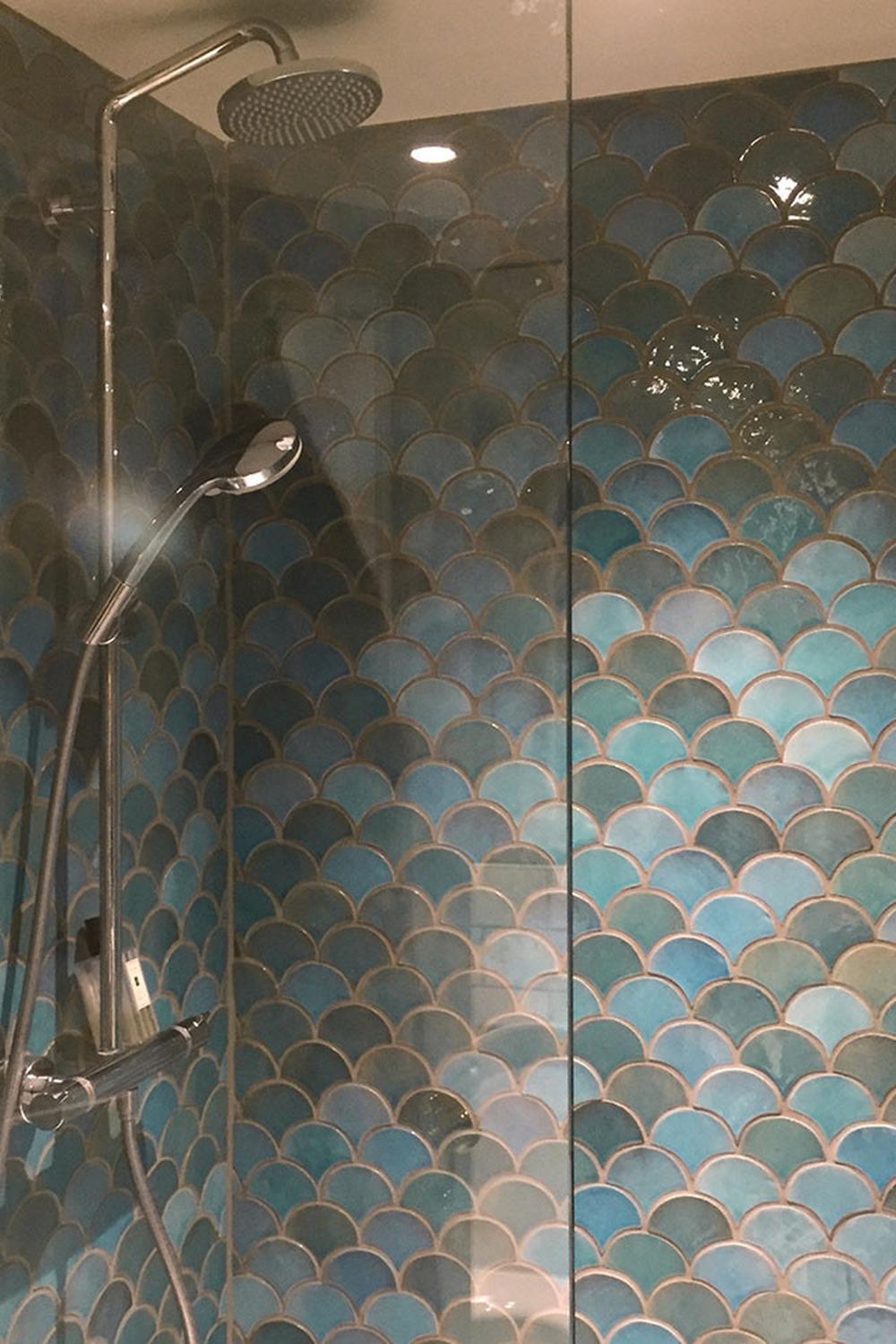 Vibrant teal and blue shower area with fish scale tiles