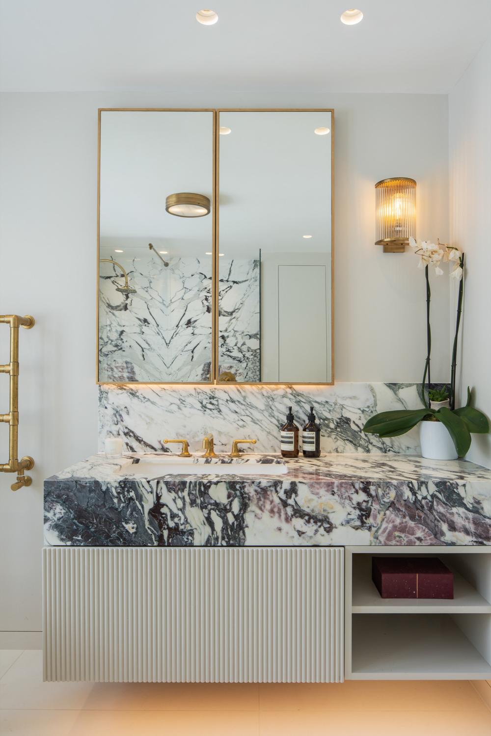 A modern bathroom featuring a floating marble vanity with a smooth, rounded countertop and an undermount sink.