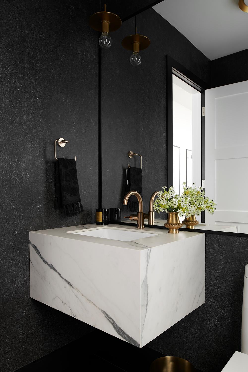 A contemporary floating marble vanity with a sleek integrated sink and elegant brushed gold faucet.