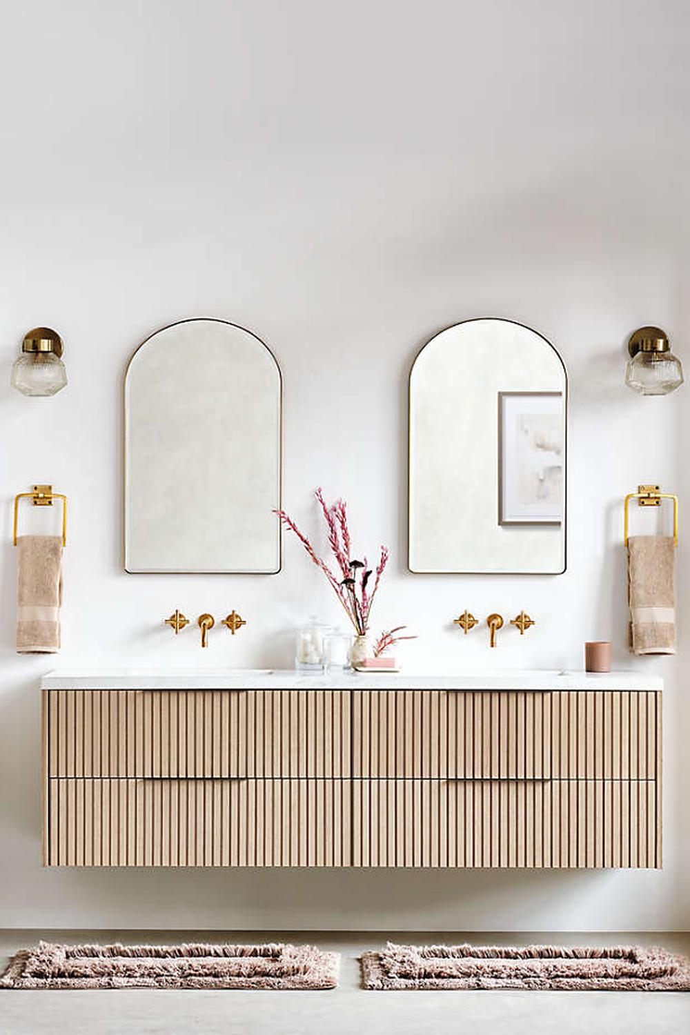 A modern bathroom with a horizontal floating marble vanity and stylish decor elements, featuring plush towels and decorative items.