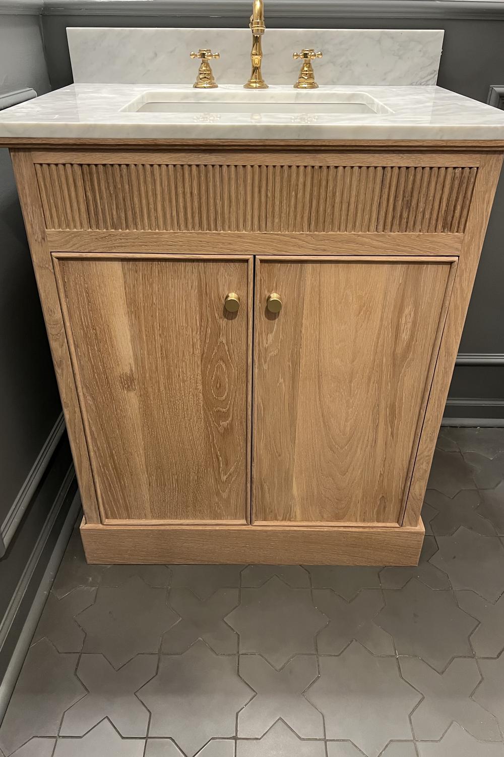 Beautiful fluted bathroom vanity with gold-tone faucets and smooth marble