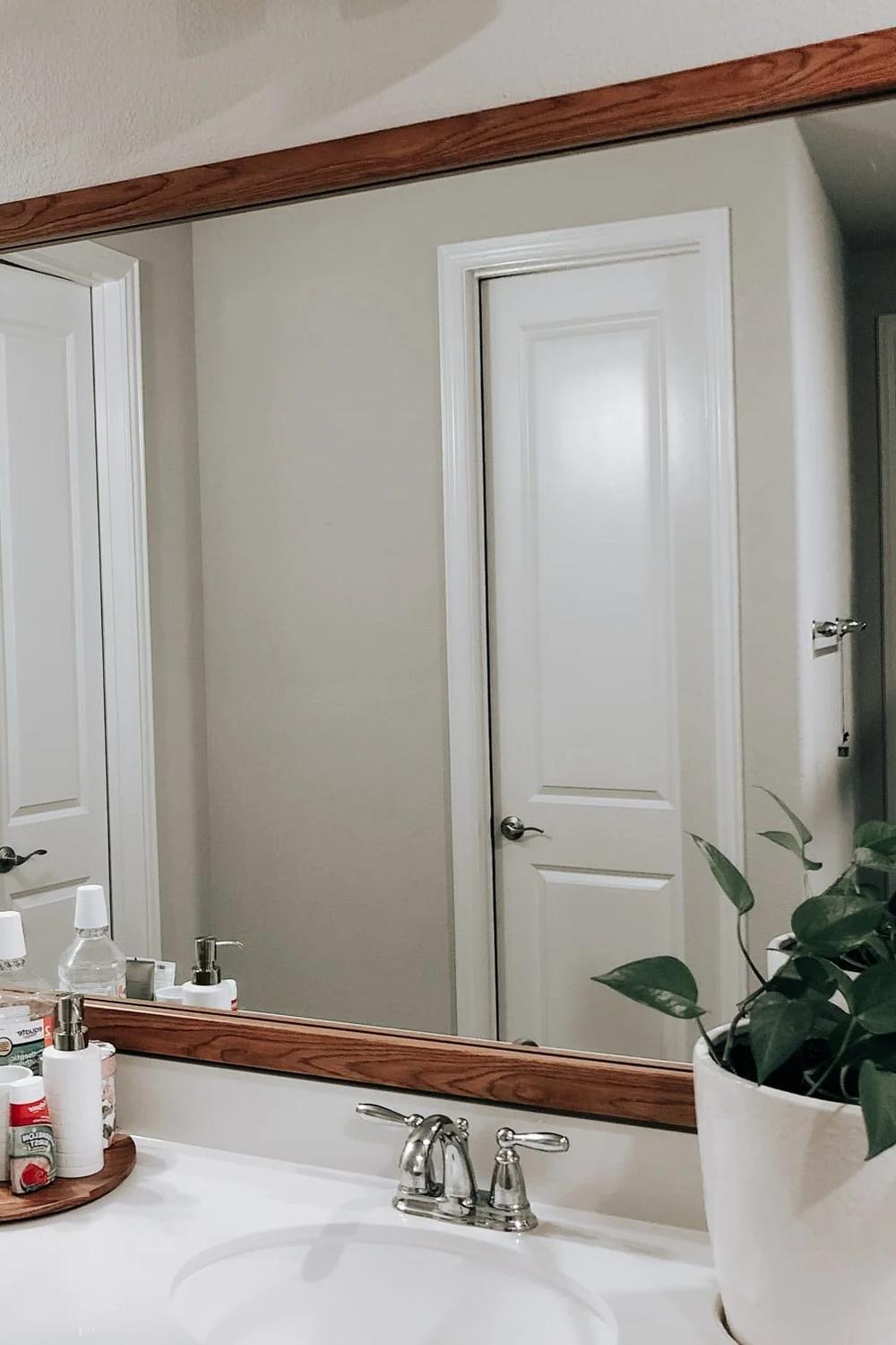 Wide wooden framed mirror showcasing a blend of elegance and a cozy atmosphere in a modern bathroom.