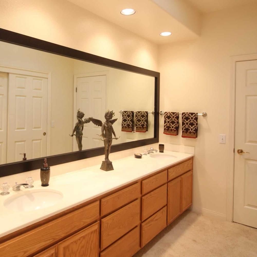 Large rectangular mirror framed in sleek metallic edges highlighting the bathroom’s minimalistic approach.