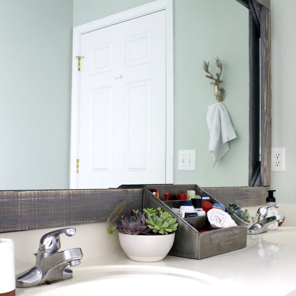 Stylish bathroom with rustic frame mirror and light green wall creating a calming, inviting atmosphere.