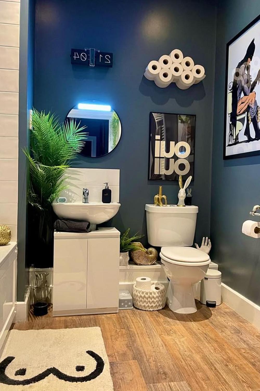 A modern bathroom featuring dark teal walls, playful decorative elements, and a colorful round mirror.