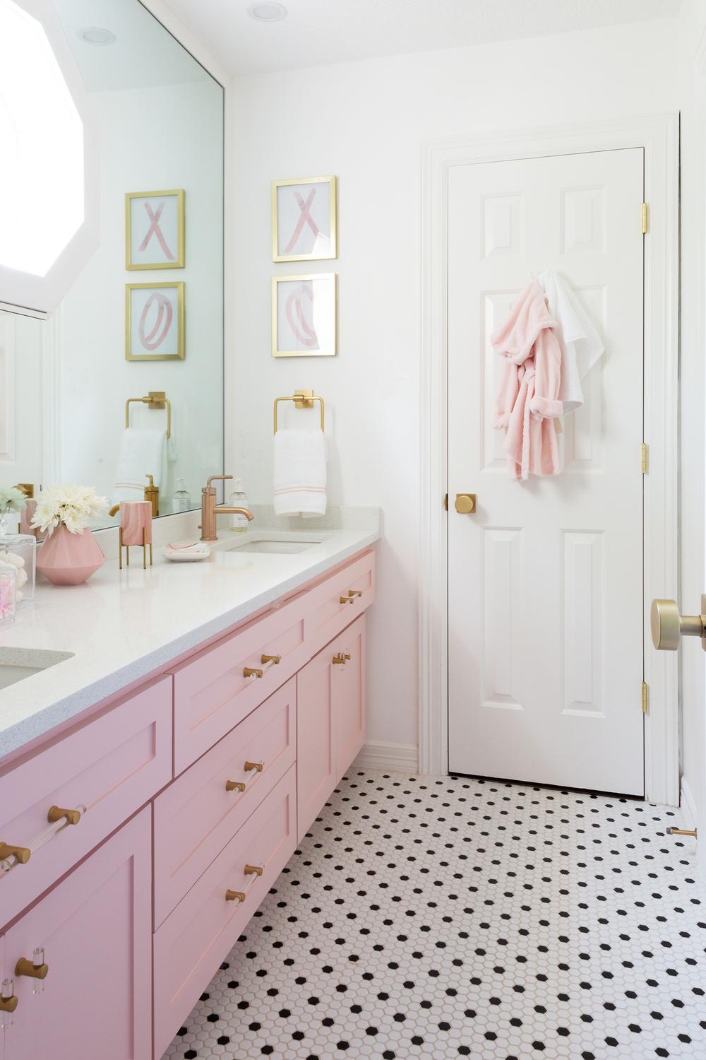 Sophisticated girly bathroom with pink cabinetry and gold accents