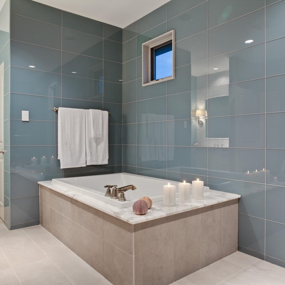 Baño con bañera central y azulejos de cristal en azul TEAL
