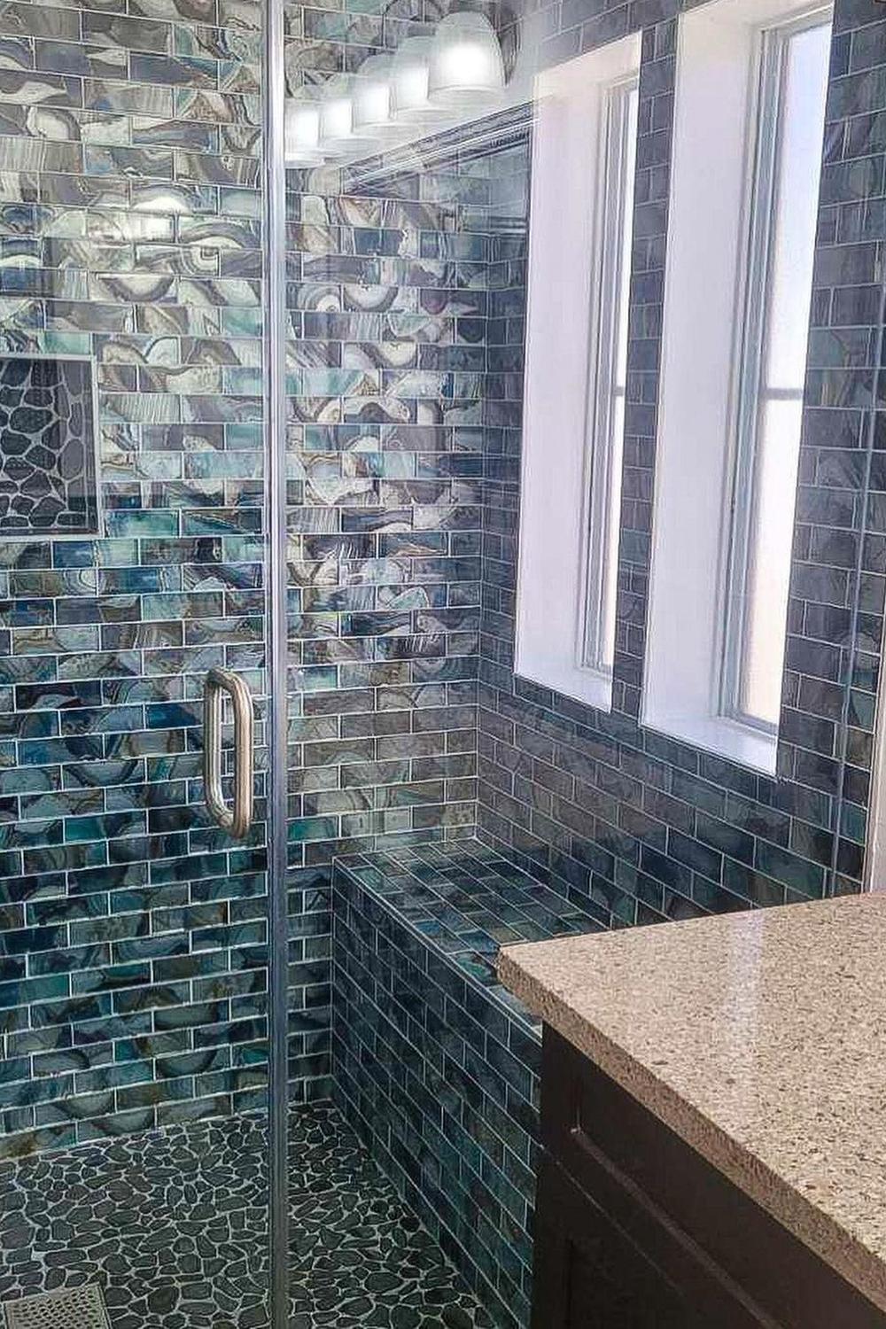 Vibrant bathroom featuring various shades of blue glass tiles and natural elements.