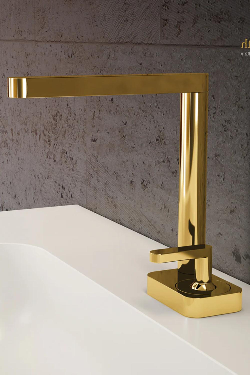 A minimalist gold faucet featuring a sleek design set against a white countertop and dark textured wall.