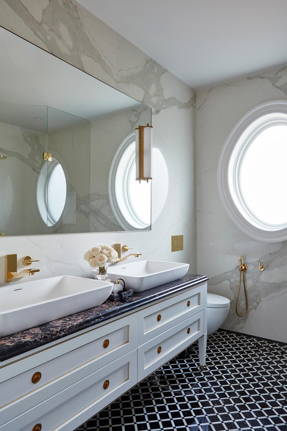 A luxurious bathroom showcasing dark accents balanced with warm gold hardware and fixtures.