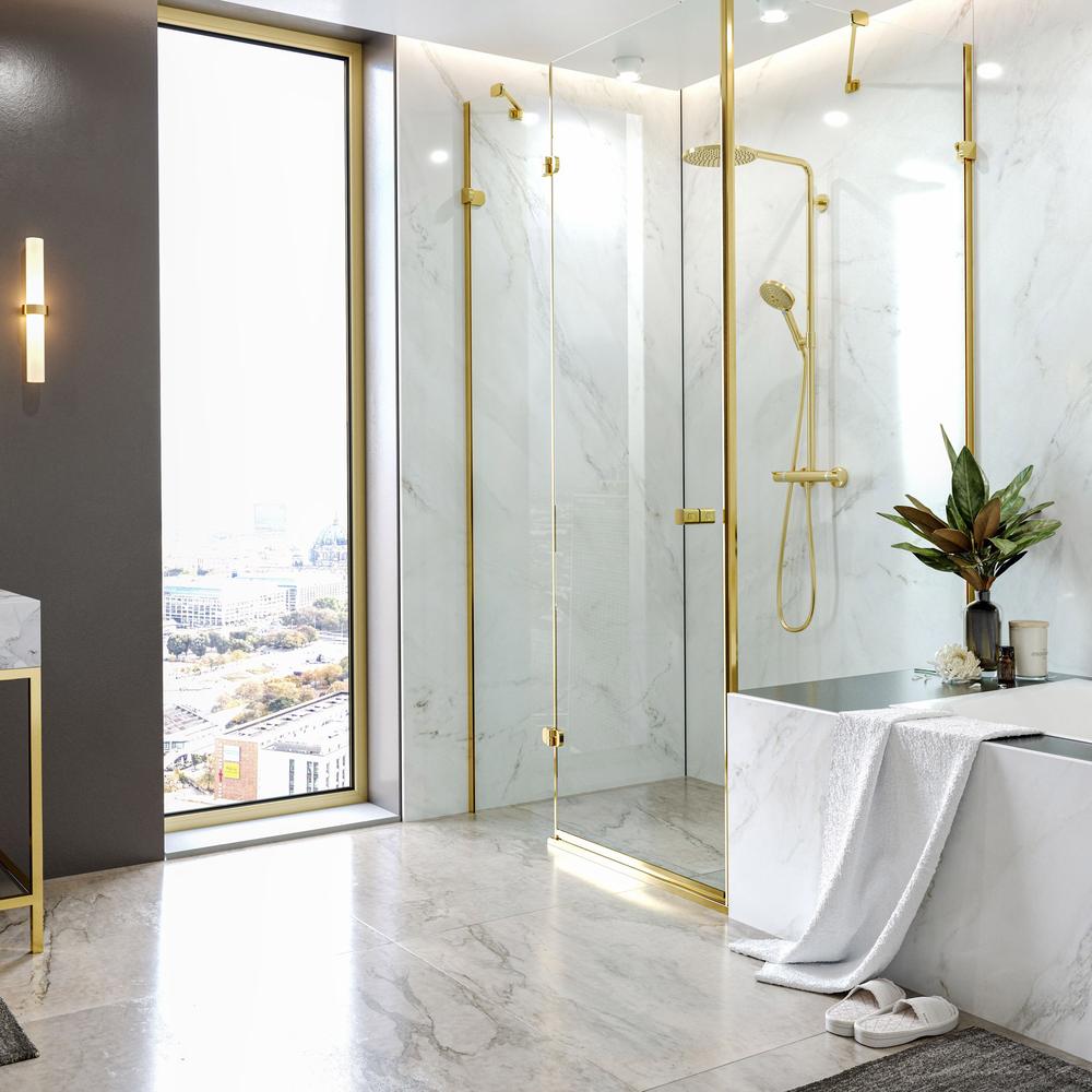 A modern bathroom featuring gold shower fixtures set against white and light grey veined marble surfaces.