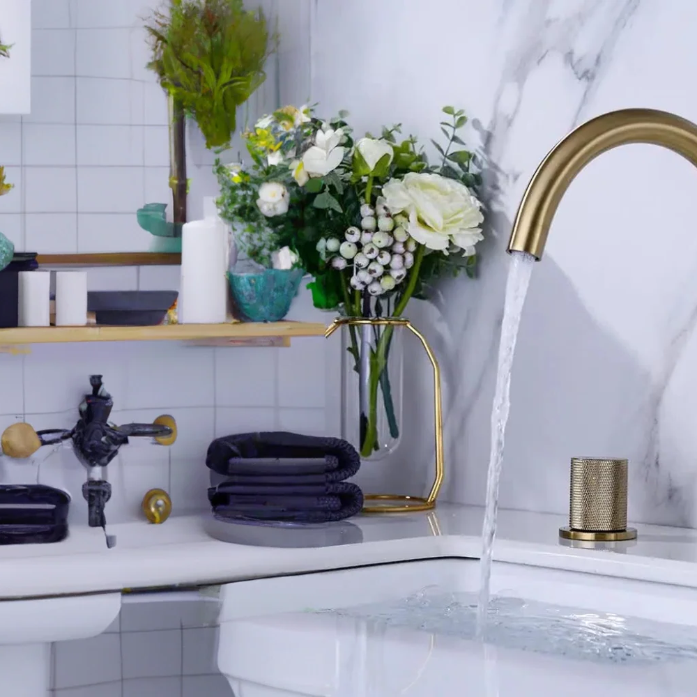 A modern bathroom featuring a gold faucet and rounded black sink, with stylish decorative touches.