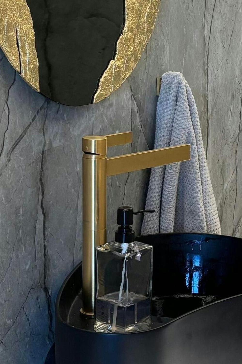 An eclectic bathroom emphasizing a white vanity and luxurious gold fixtures.