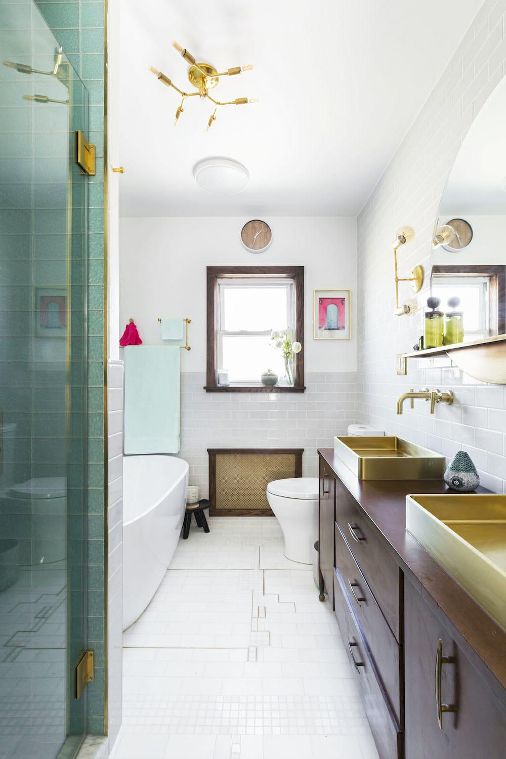 An inviting bathroom featuring luxurious gold faucets, white walls, and elegant green accents.