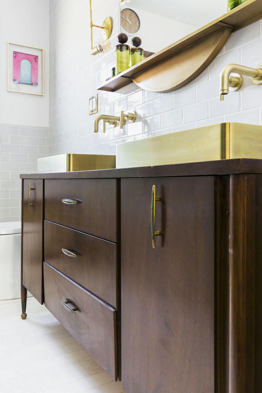 A mid-century inspired bathroom featuring gold fixtures and rich wooden elements.