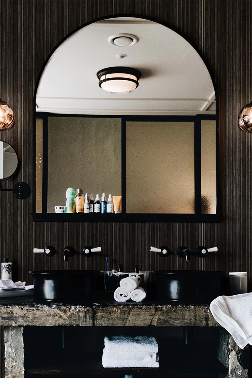 Baño rústico con papel pintado de hierba oscuro y detalles en bronce.