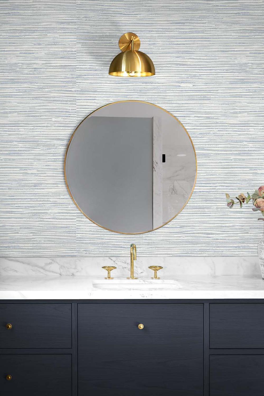 Baño moderno con papel pintado gris, iluminación cálida y decoración elegante.