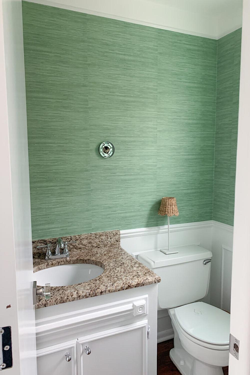 Light green retreat bathroom featuring soft grasscloth wallpaper and elegant features.