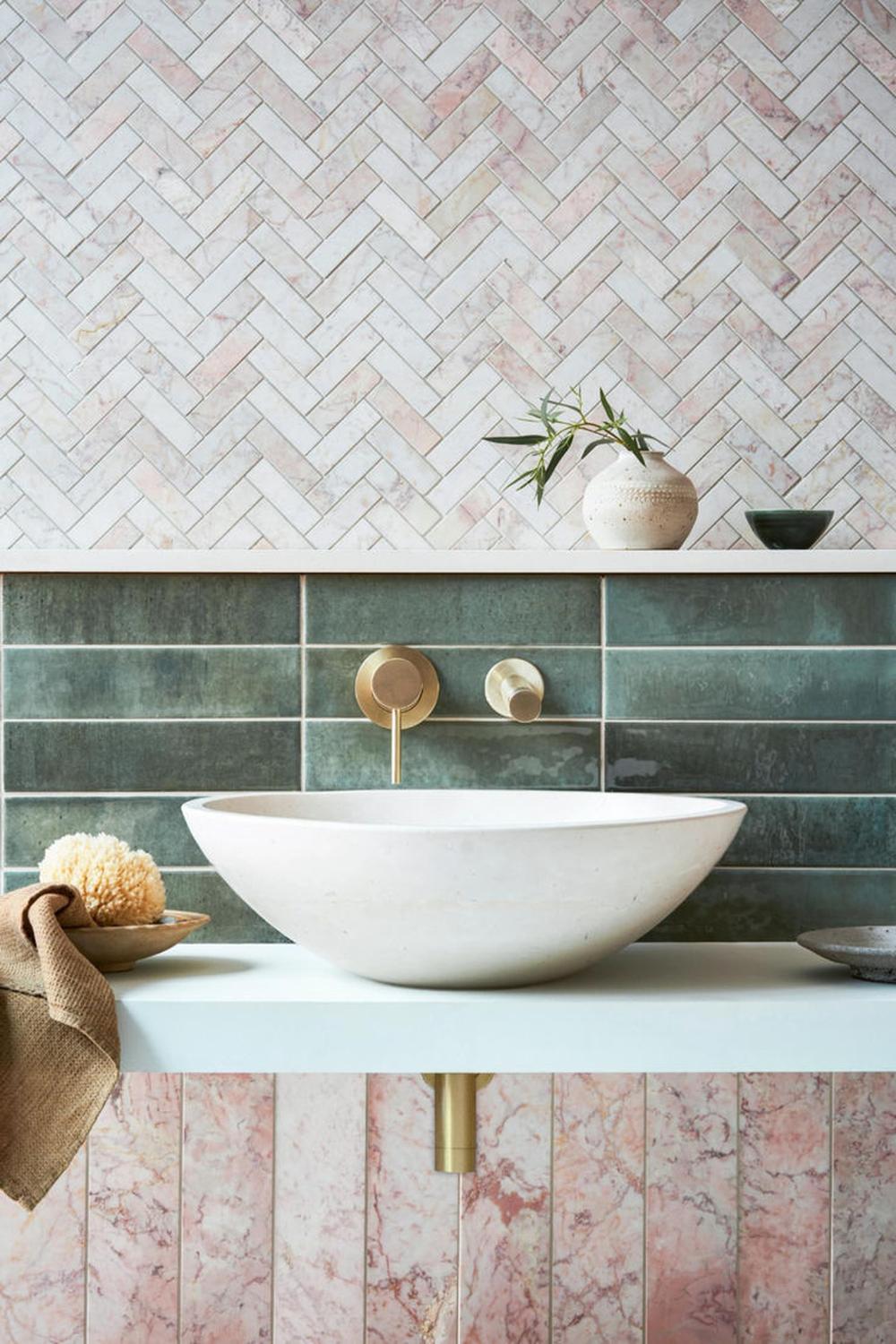 Baño con azulejos de fondo rosa y verde en sarga, junto a un elegante lavabo.