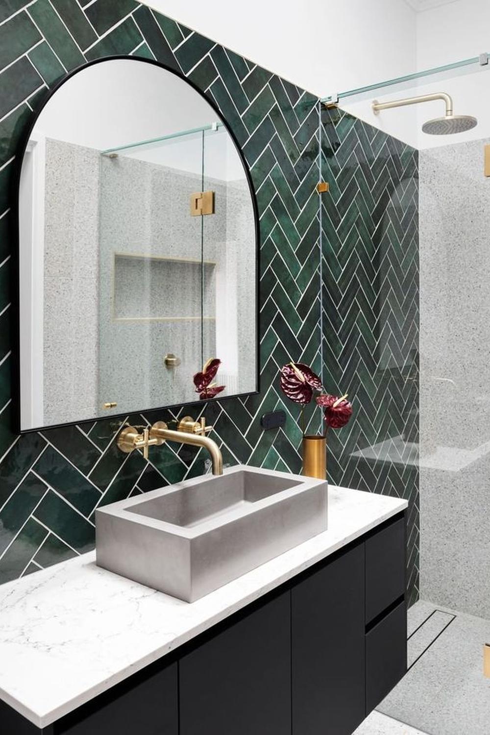 Baño con azulejos verde en sarga y lavabo de hormigón.