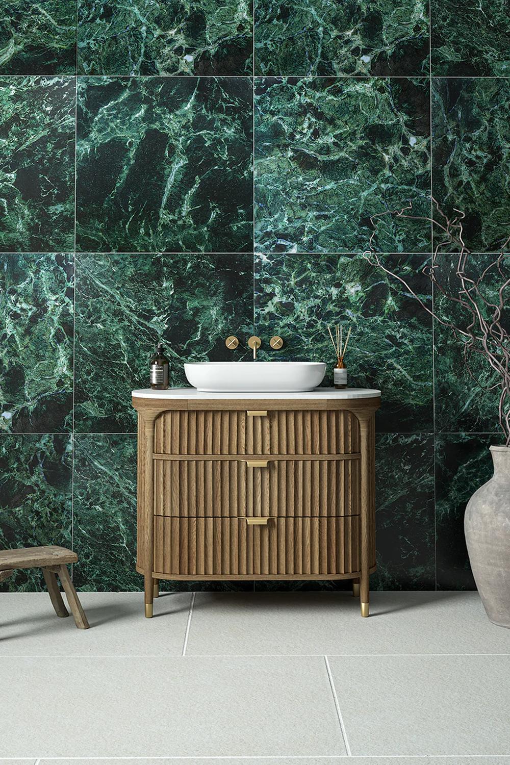 A bathroom showcasing a feature wall of green marble, stylish wooden vanity, and elegant decor.