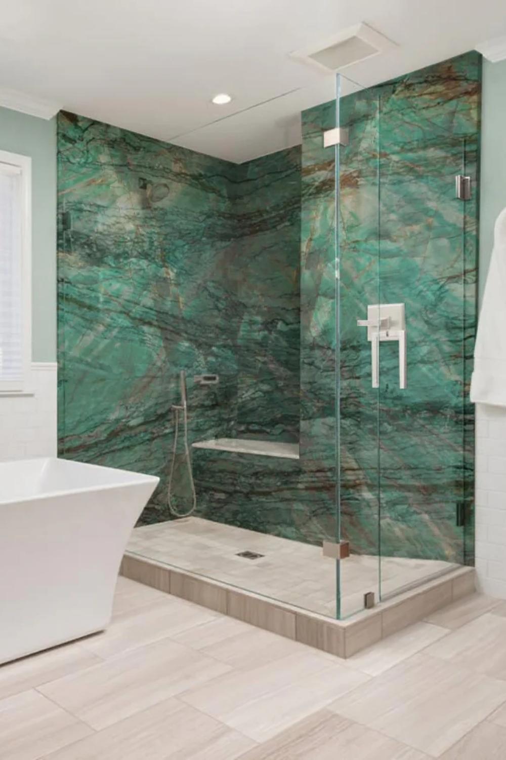 A modern bathroom with a green marble accent wall and elegant freestanding bathtub.