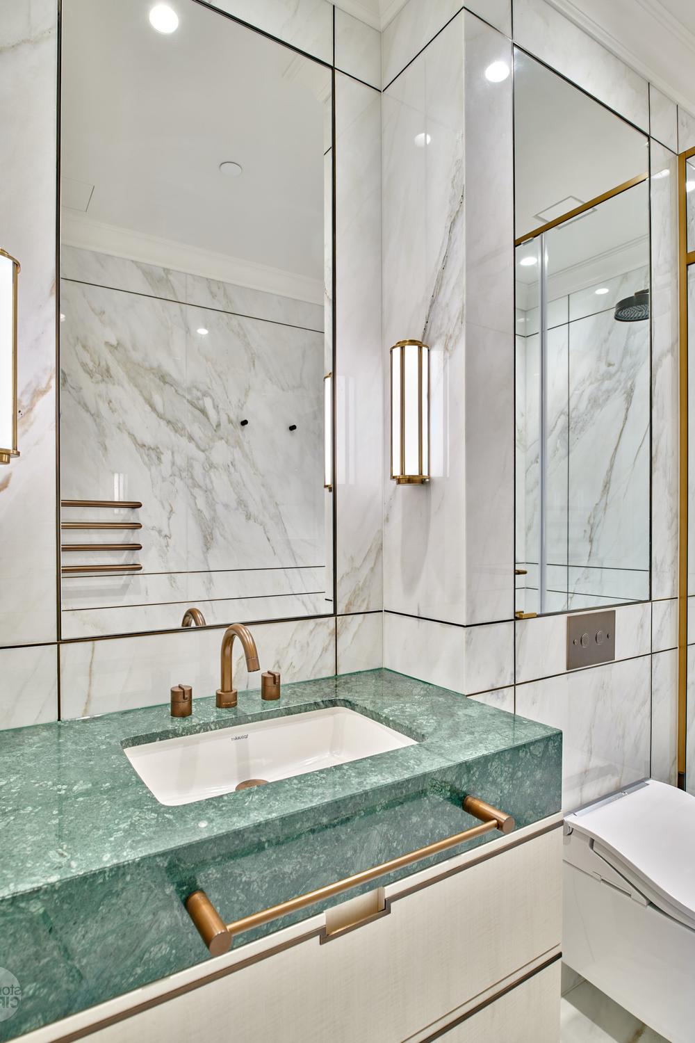 A chic bathroom with a green marble vanity, brass accents, and stylish decor.