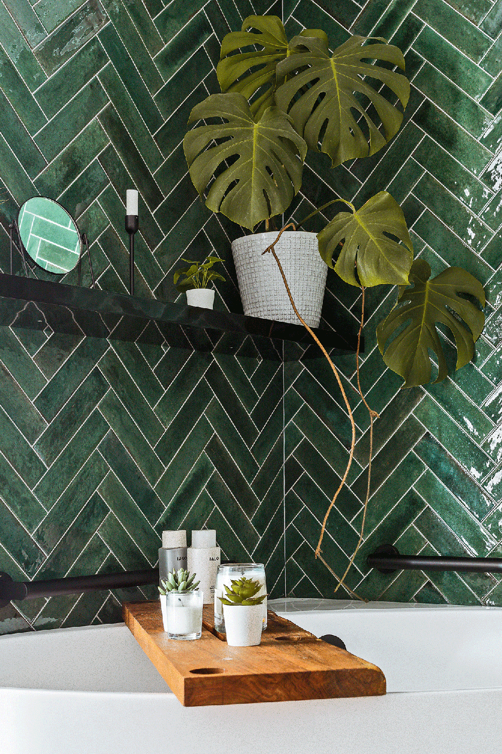 Bathroom with herringbone patterned green tiles and wooden bath accents.