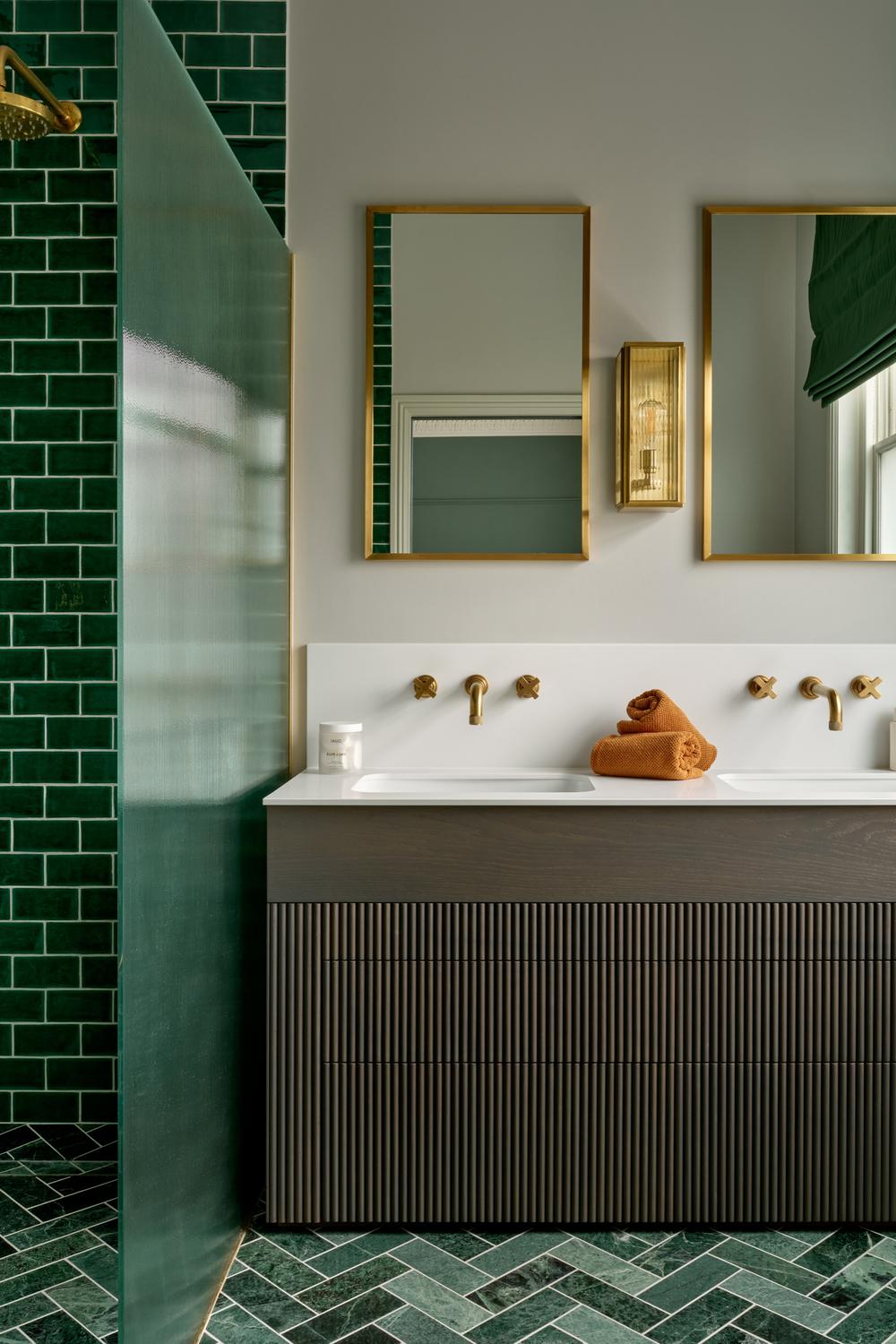 Bathroom with dark green tiles contrasted by light flooring in a modern design.