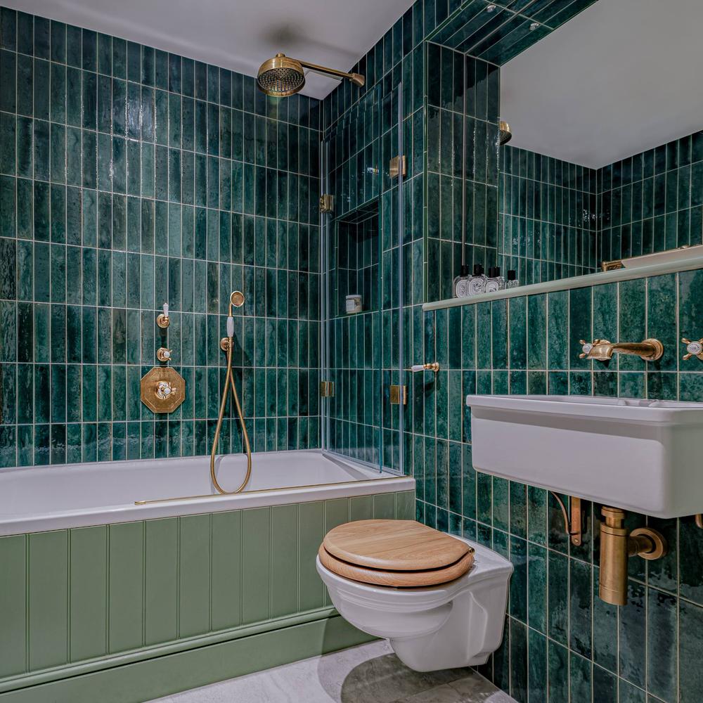 Bathroom featuring a modern freestanding bathtub with eye-catching green tile designs.