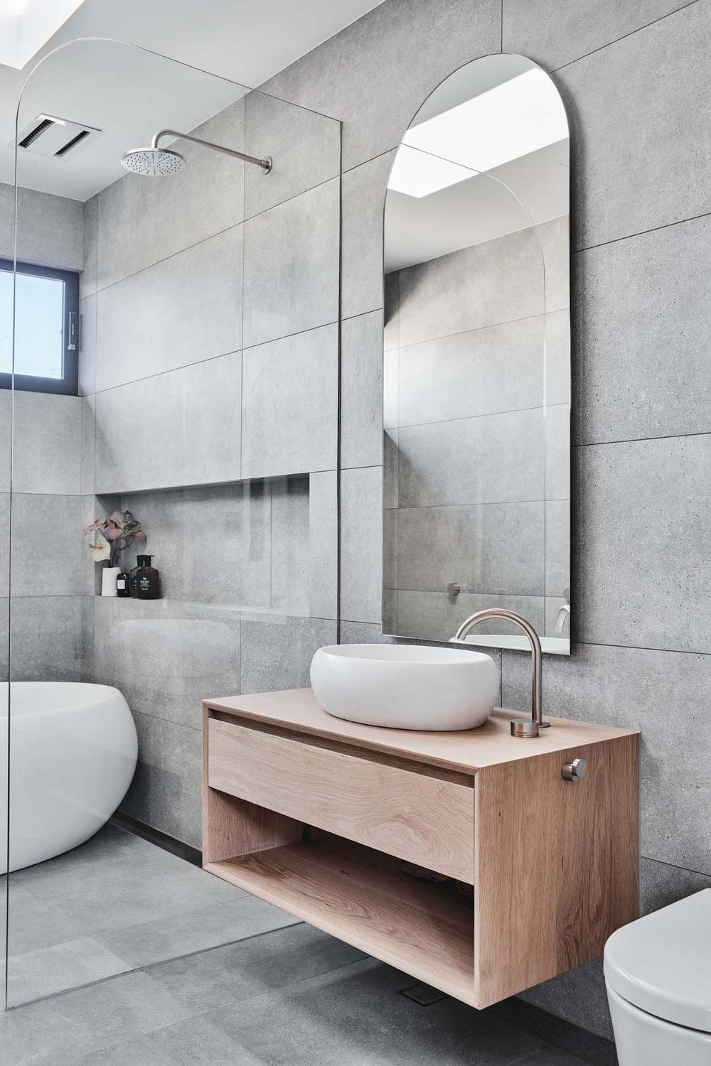 Shower area with glass enclosure and minimalist design in a modern grey tile bathroom
