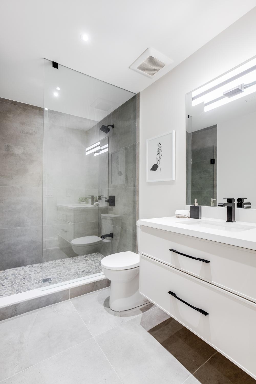 Freestanding white bathtub complements grey tiles in a modern bathroom