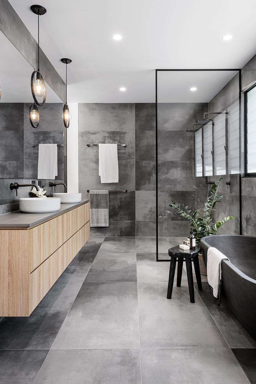 Bathroom showcasing textured grey wall tiles contrasted with patterned flooring