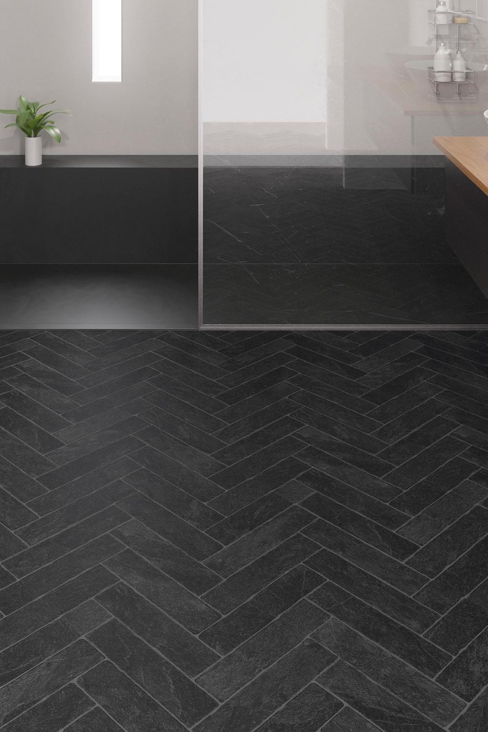 Bathroom floor featuring black herringbone tiles laid in chevron pattern.