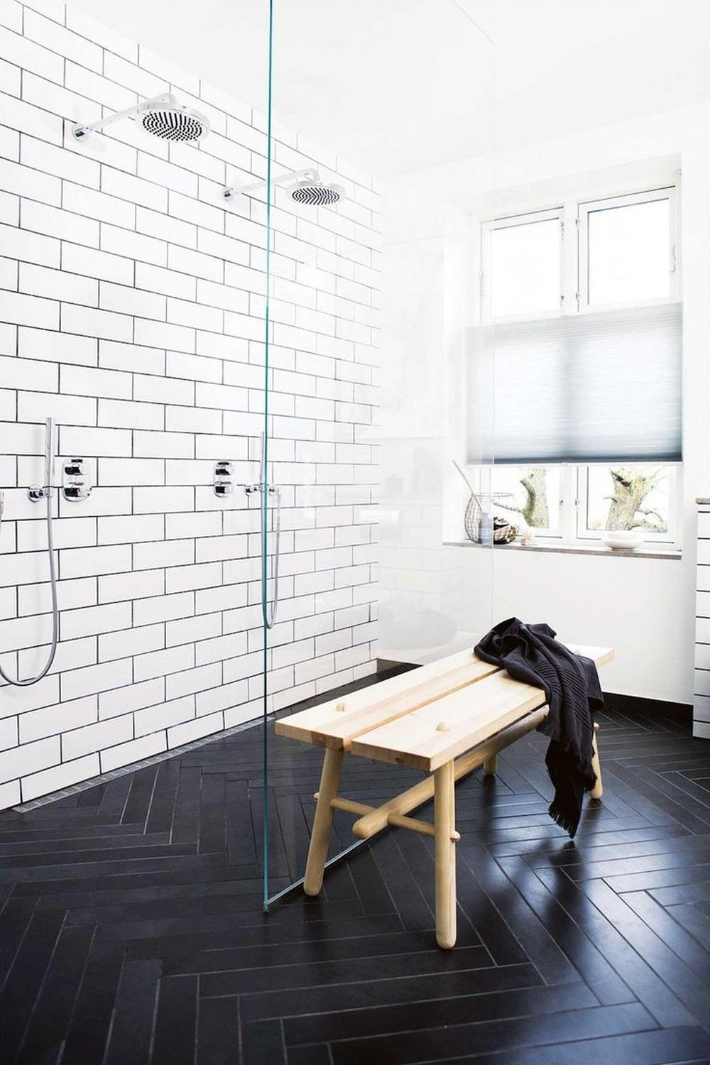 Modern bathroom with herringbone black tiles and contrasting white tile wall.