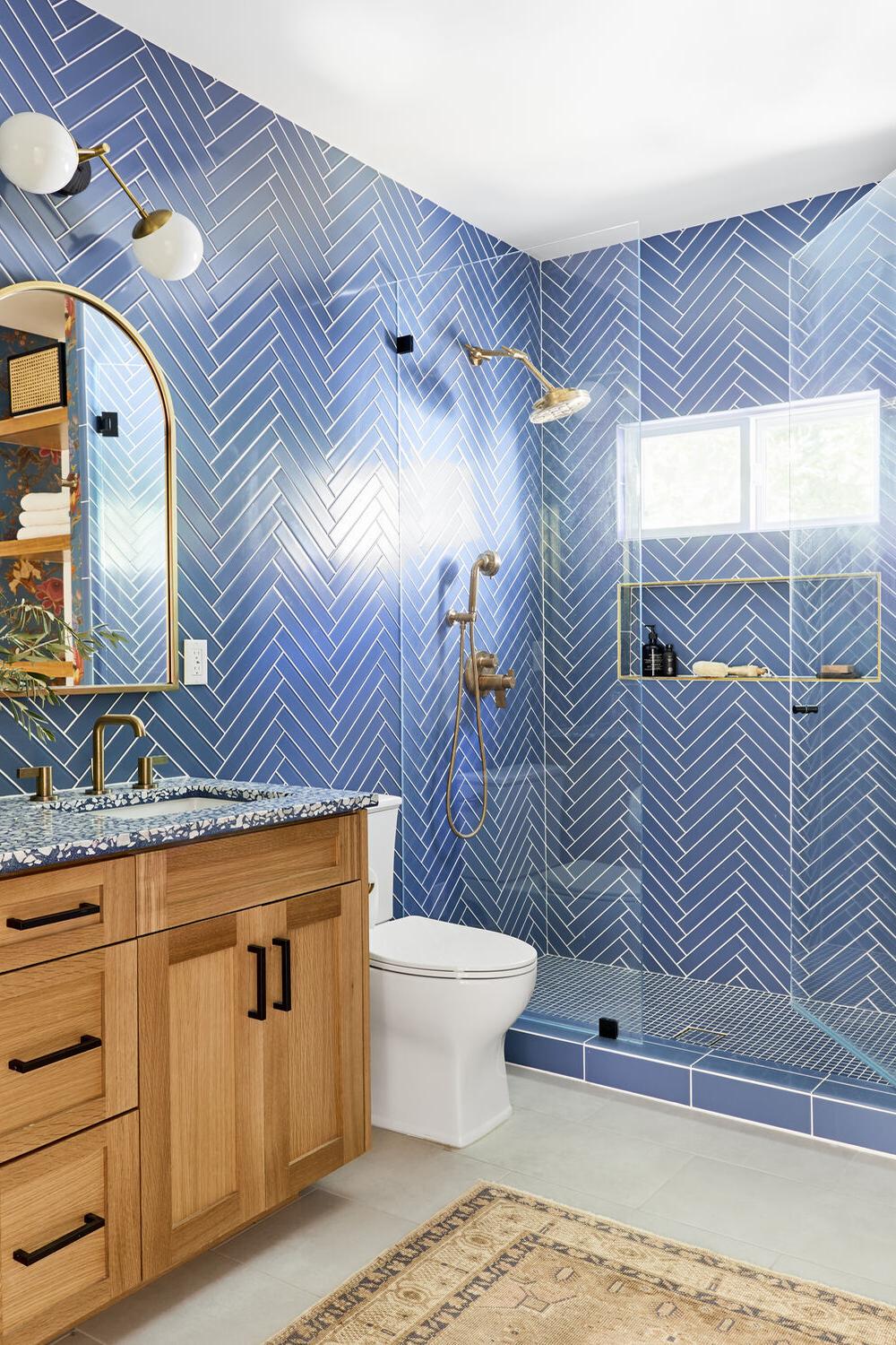 Elegant blue herringbone tiles surround a contemporary shower, contributing to a stylish bathroom design.
